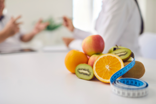 Fruit with a tape measure and a dietitian talking to client in the background