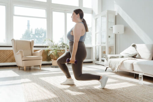 Woman exercising by lifting free weights in home