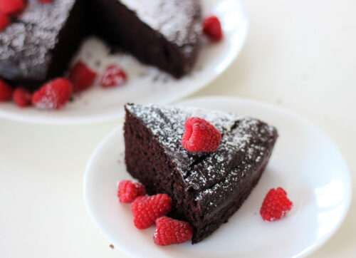 Slice of chocolate cake with powdered sugar and fresh raspberries
