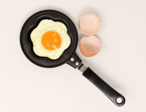 Egg cooking in pan next to egg shell