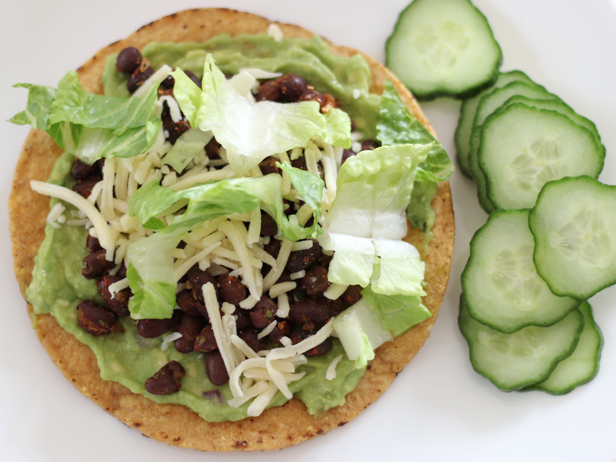 Black bean tostada with guacamole and cucumber slices